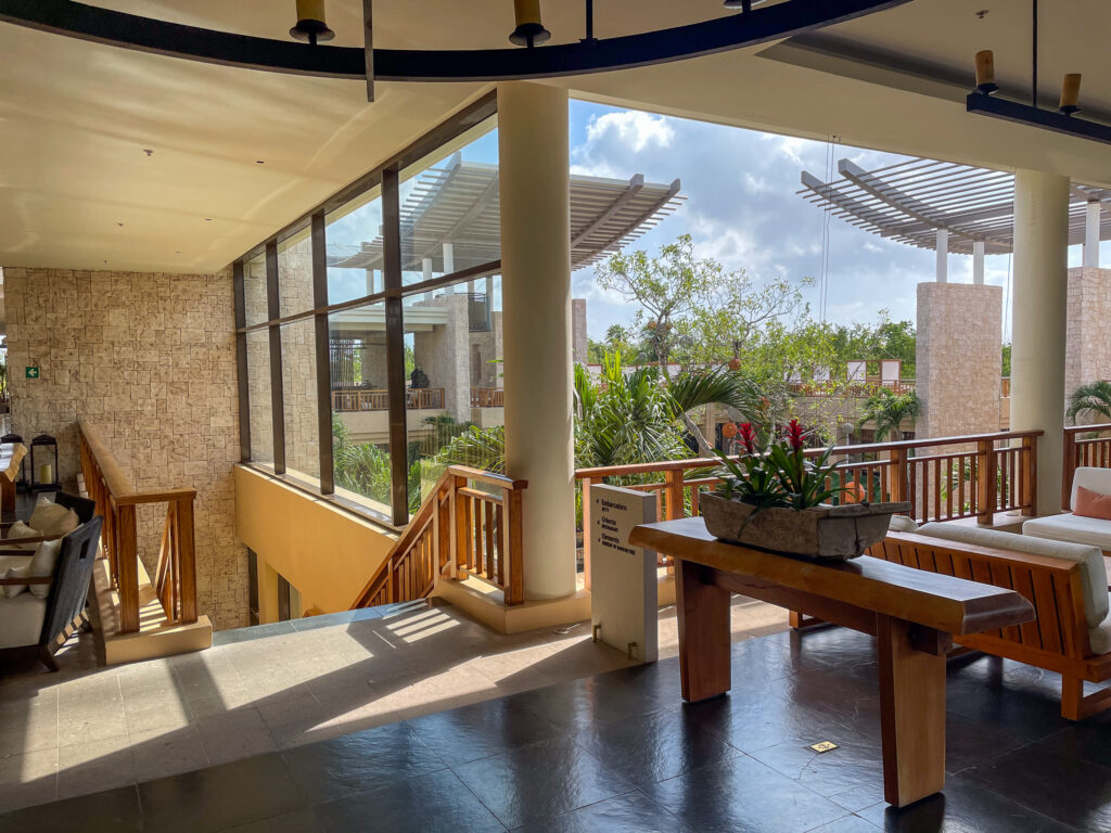 The open-air lobby lounge, timber sofas and a stone planter looking out to the pergolas and gardens