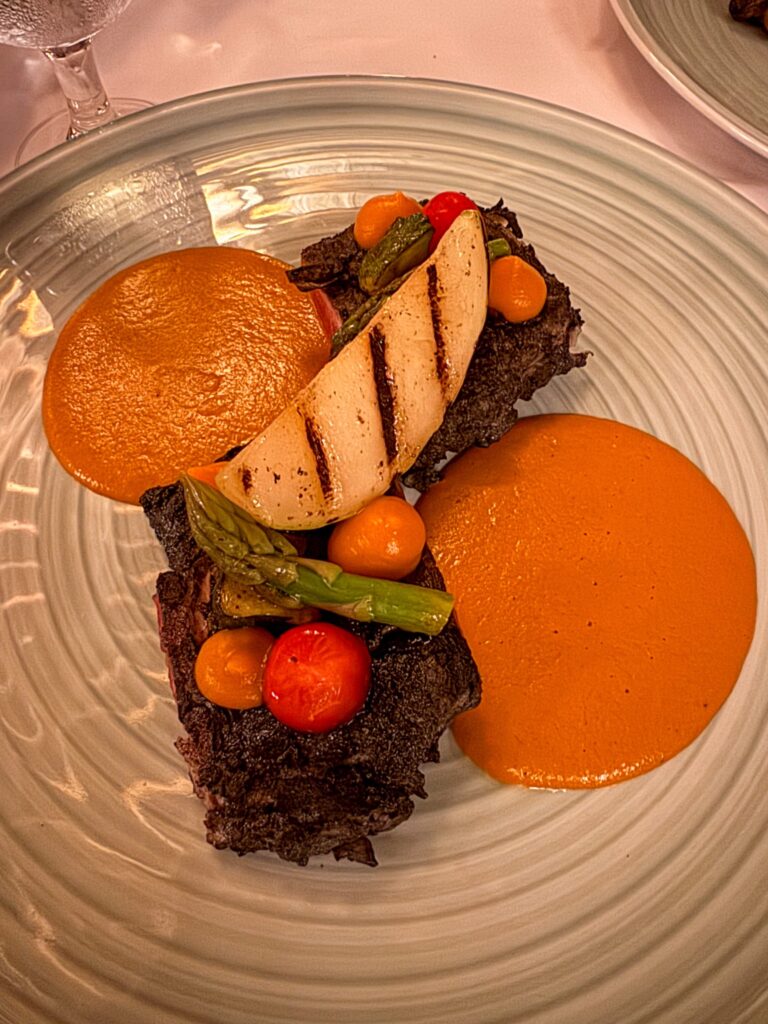 Grilled beef with charred pear, asparagus and cherry tomatoes between two orange sauce pools