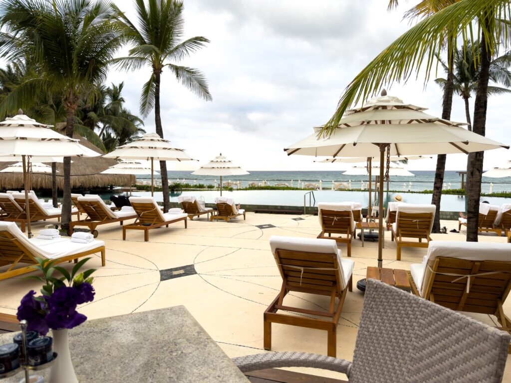 White parasols and teak loungers on a stone terrace running to an infinity pool above the sea