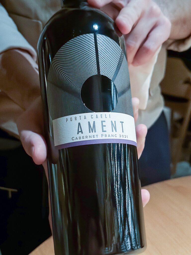 A hand holding a bottle of Porta Caeli Ament Cabernet Franc