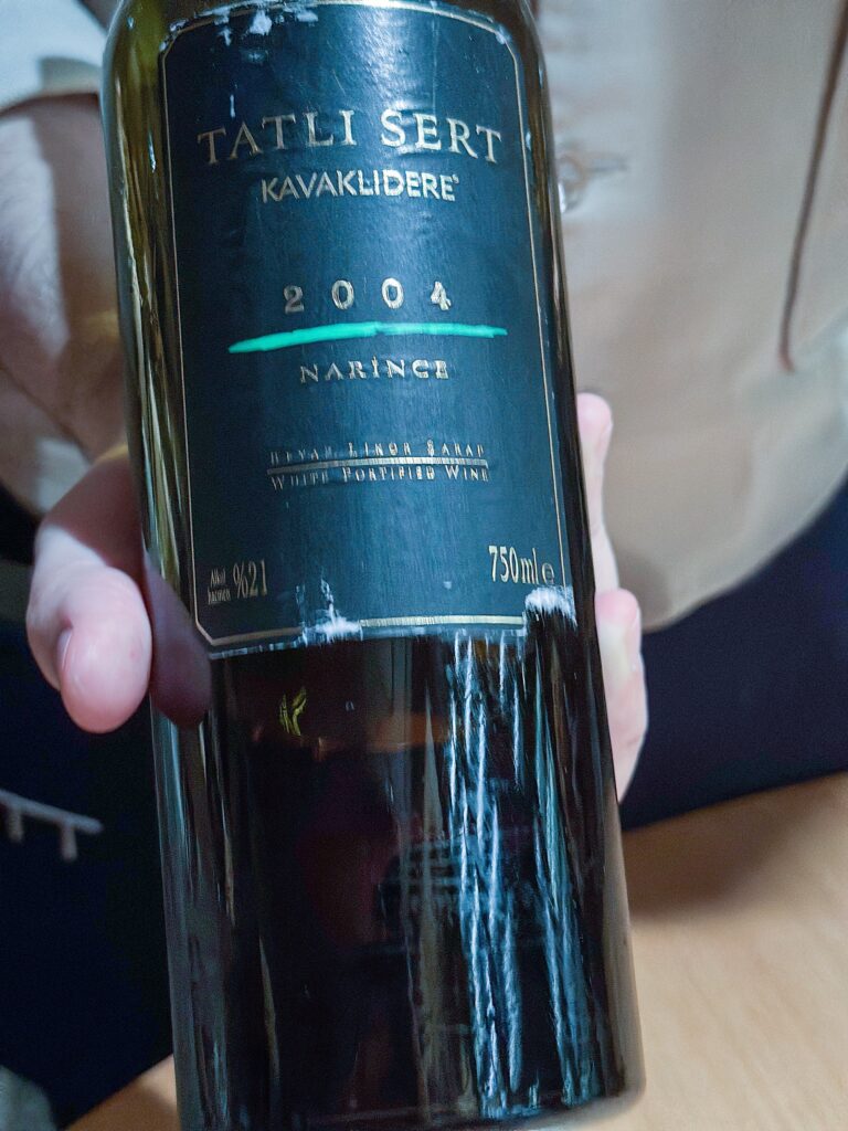 A hand holding a bottle of Kavaklidere Tatli Sert 2004, a fortified white made from Narince grapes