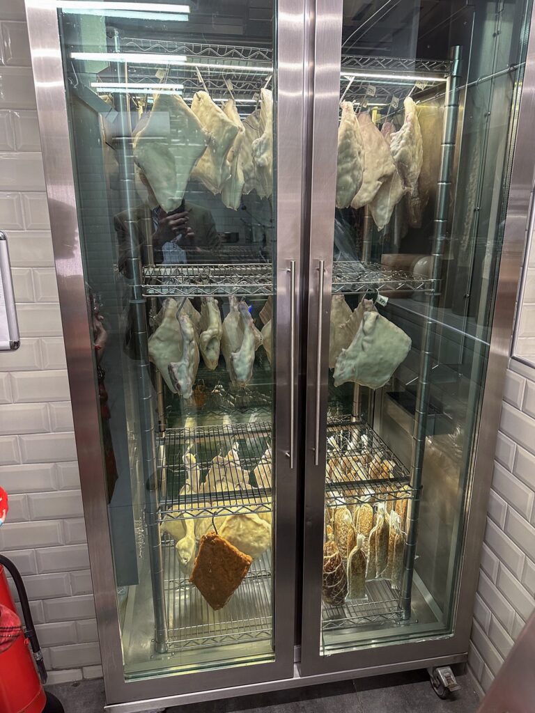 Two glass-fronted cabinets hung with drying fish and flatbreads on wire racks