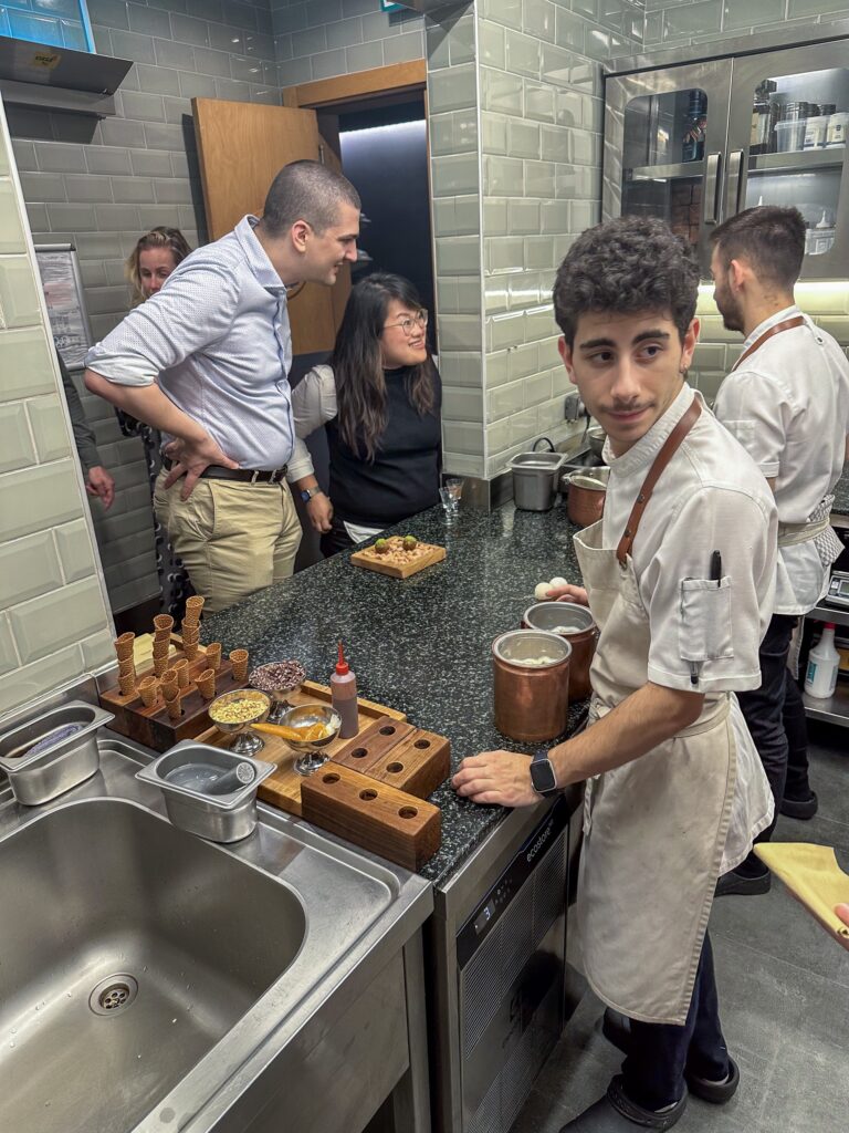 Cooks working at the kitchen counter with wooden stands of cones and small bowls of garnish