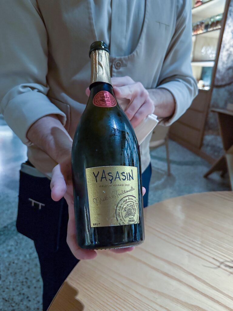 A sommelier presenting a bottle of Yasasin brut sparkling wine over the table