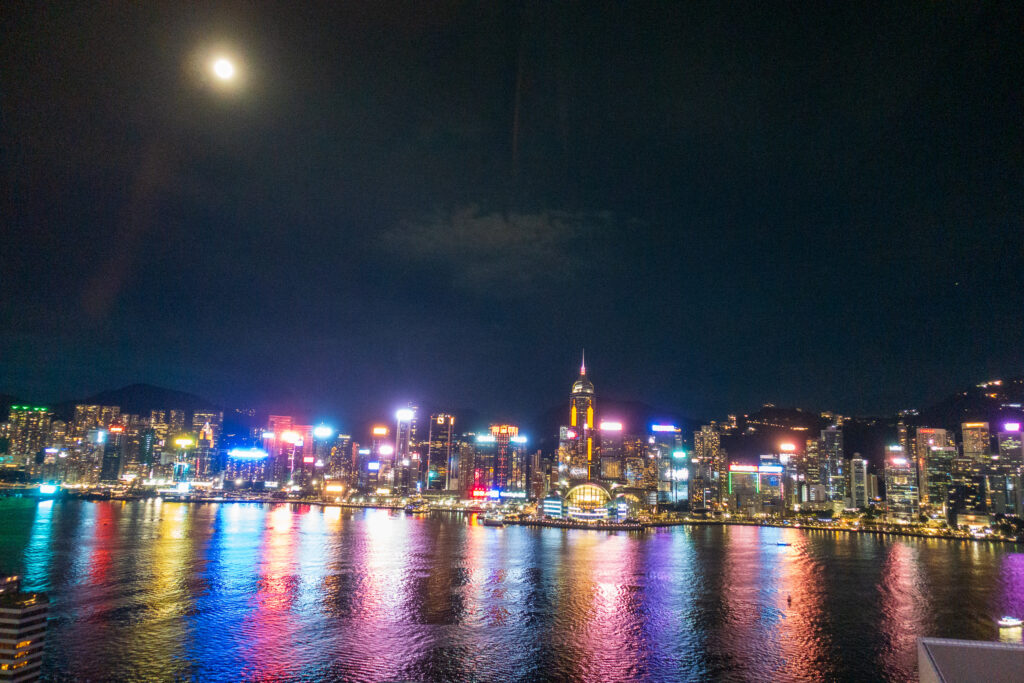 A full moon over the lit Hong Kong Island skyline, its colour reflected the length of the harbour