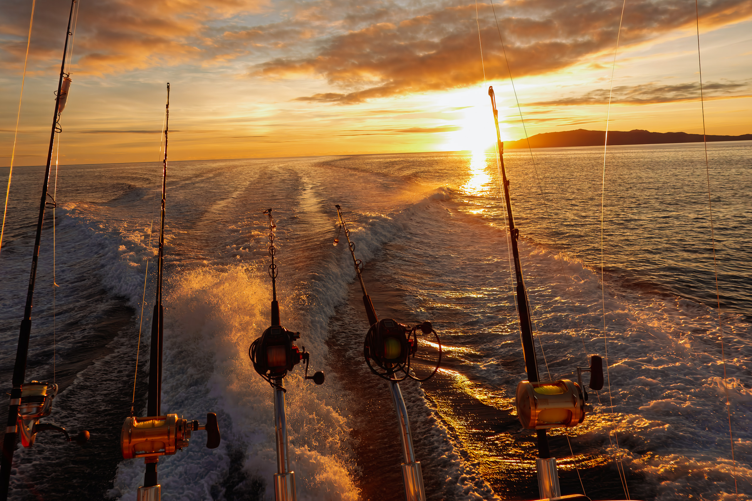 Trolling rods silhouetted against sunrise on the run south from Kokomo, Fiji