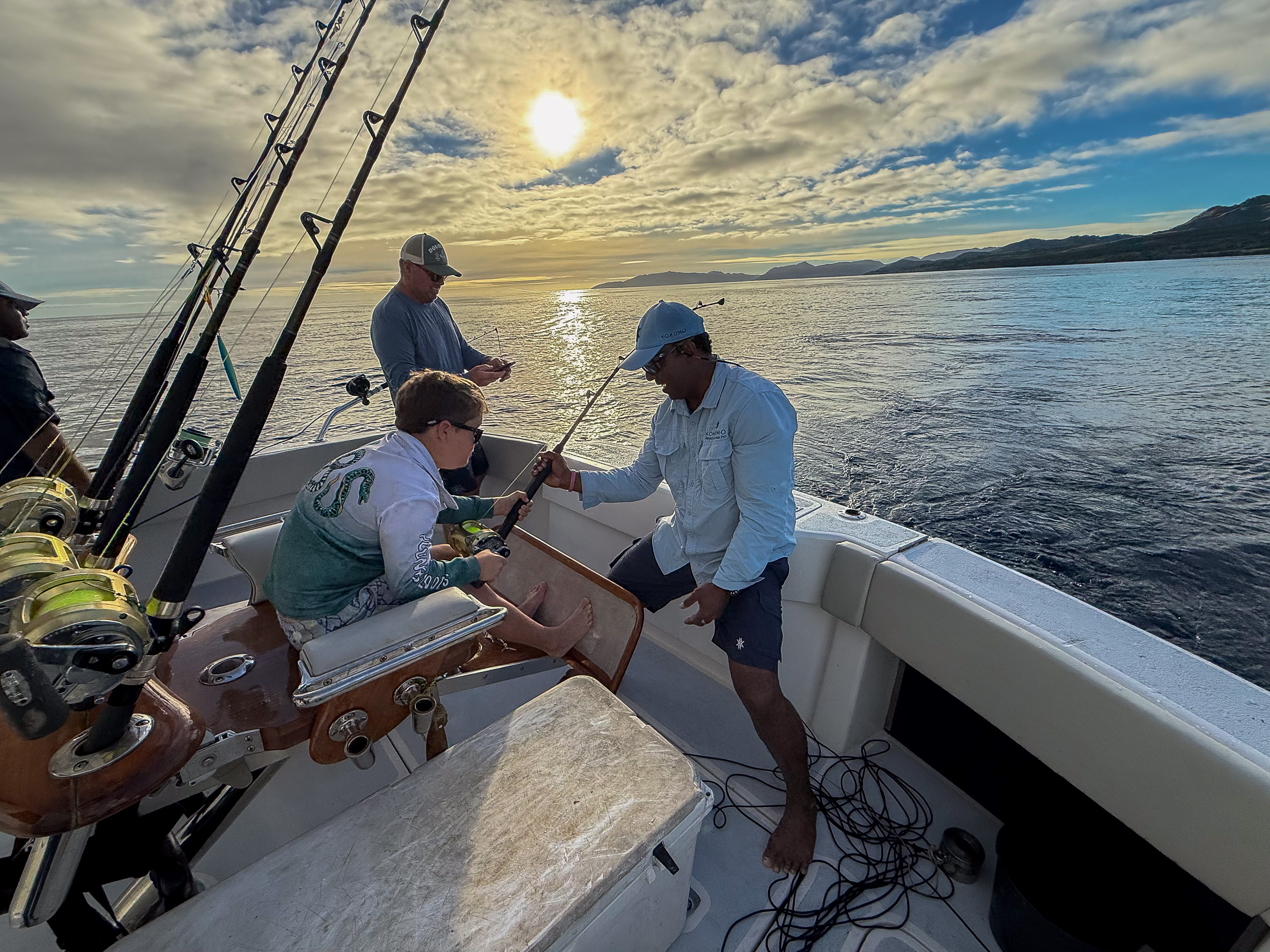 Anglers working a hooked fish at the stern of a sportfishing boat