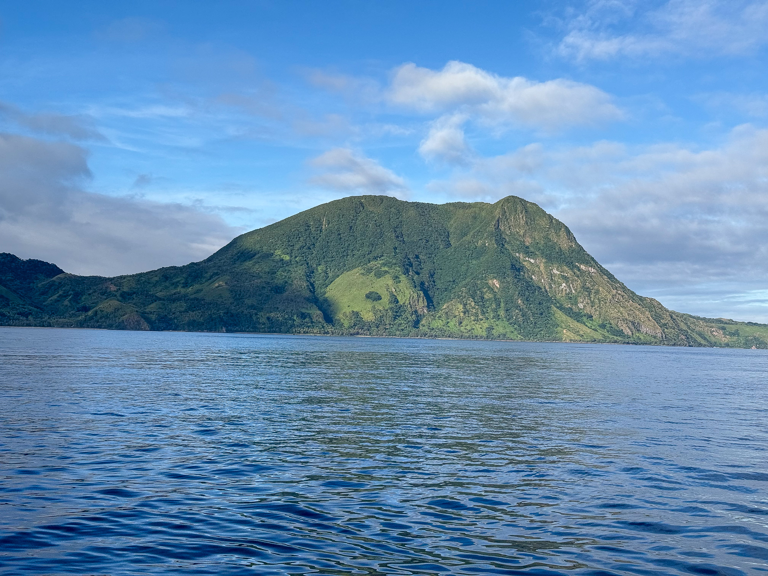 A steep green island rising out of open ocean off Kadavu, Fiji