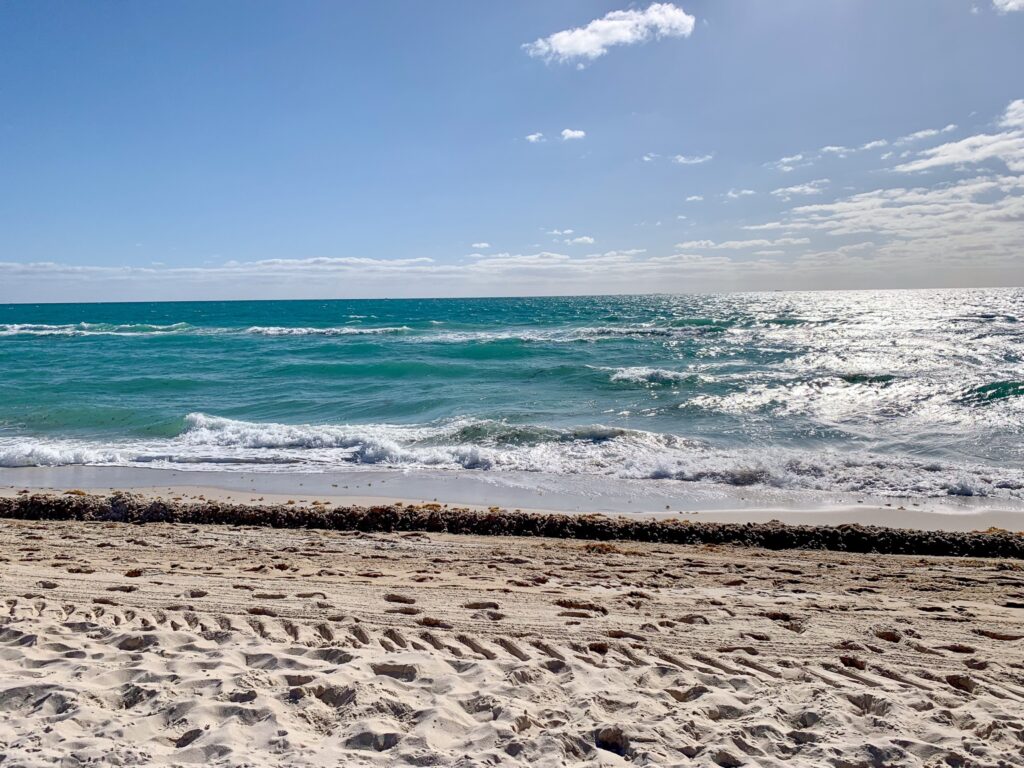 Turquoise surf breaking on the wide sand of Miami Beach on a clear, breezy morning
