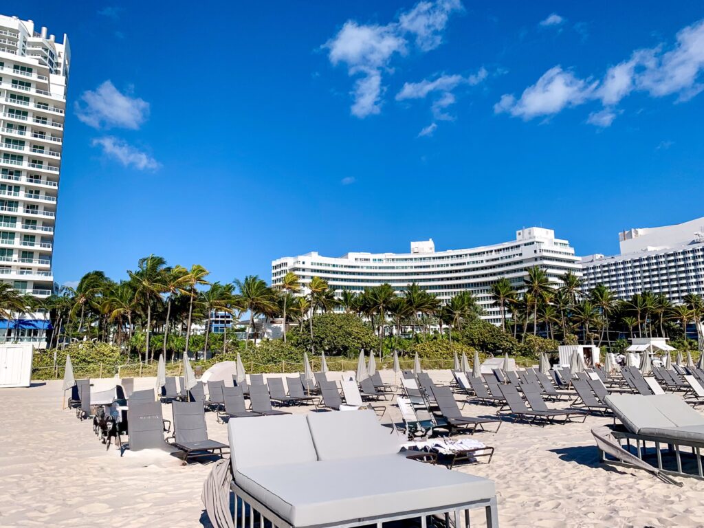 Rows of loungers and folded umbrellas on the sand in front of the curved white Chateau tower