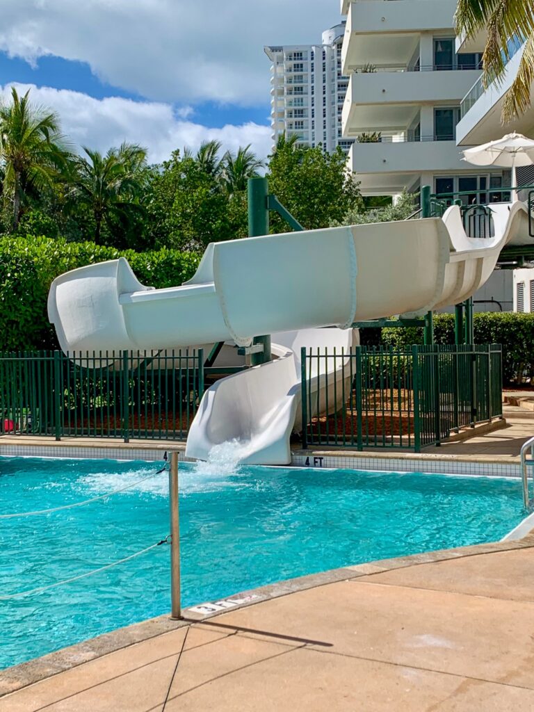 White waterslide curving down into the family pool below the tower balconies