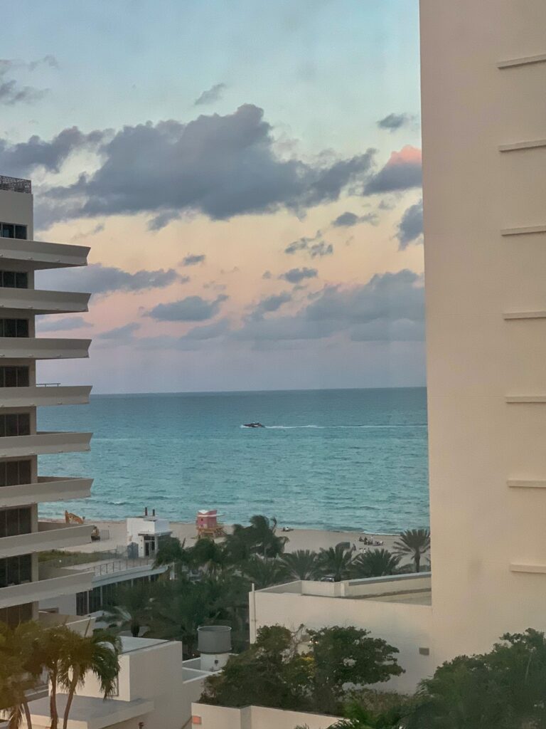Pastel dusk over the Atlantic framed between two hotel towers, a jet ski crossing the water