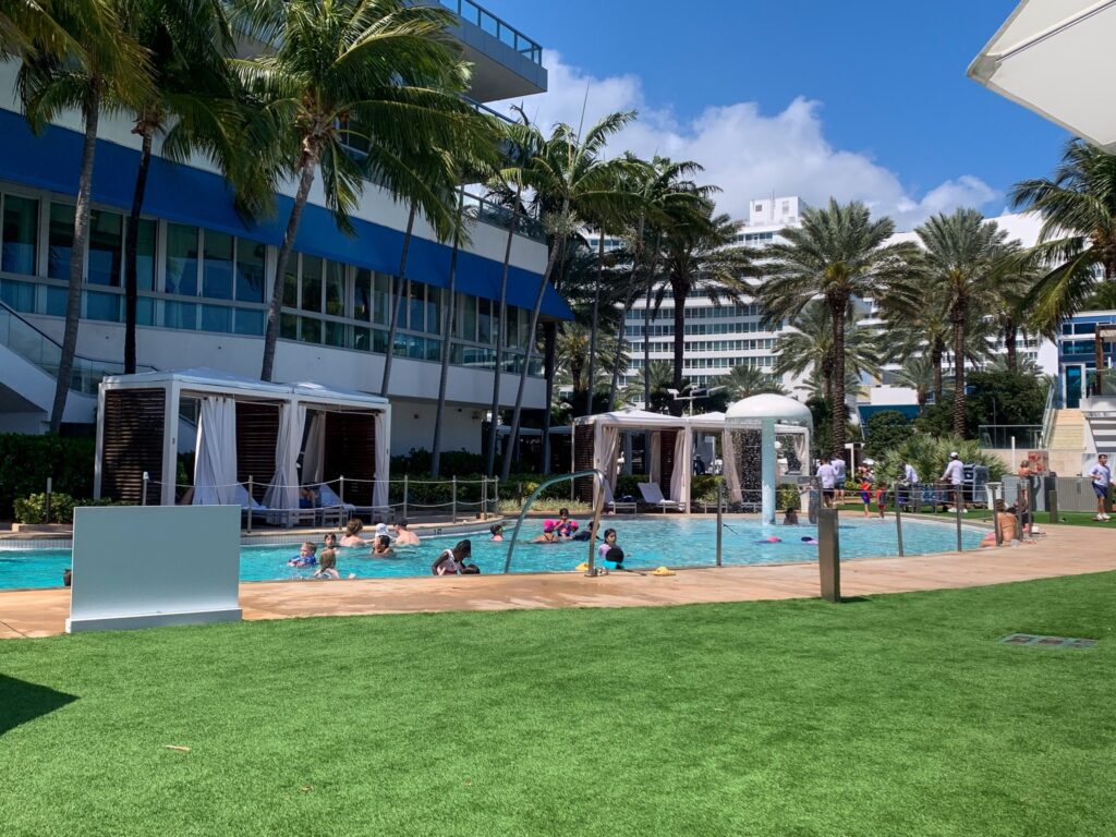 Family pool with cabanas and a turf lawn in front of the blue trimmed tower
