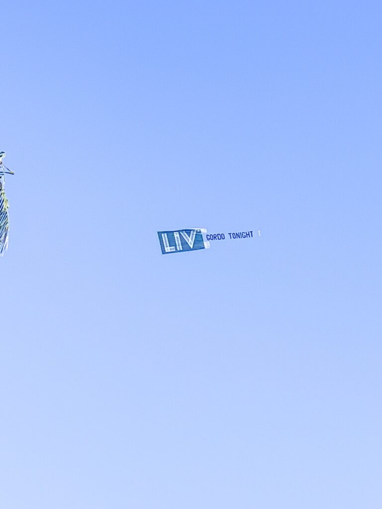 Aerial banner advertising a night at LIV drifting across clear blue sky above the hotel