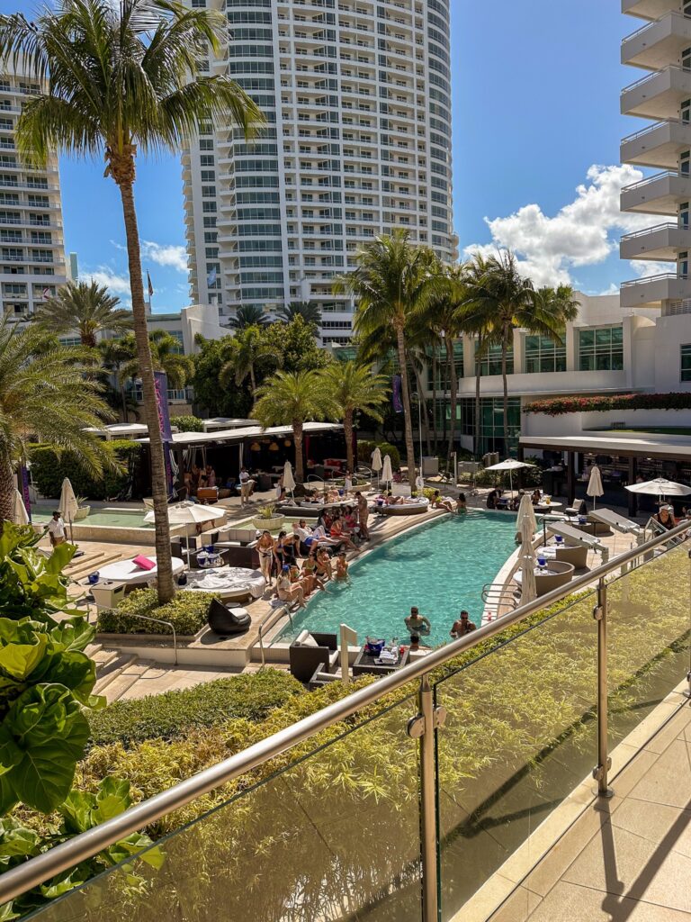 Elevated view over the palm lined pool club, daybeds and cabanas below the high rise towers