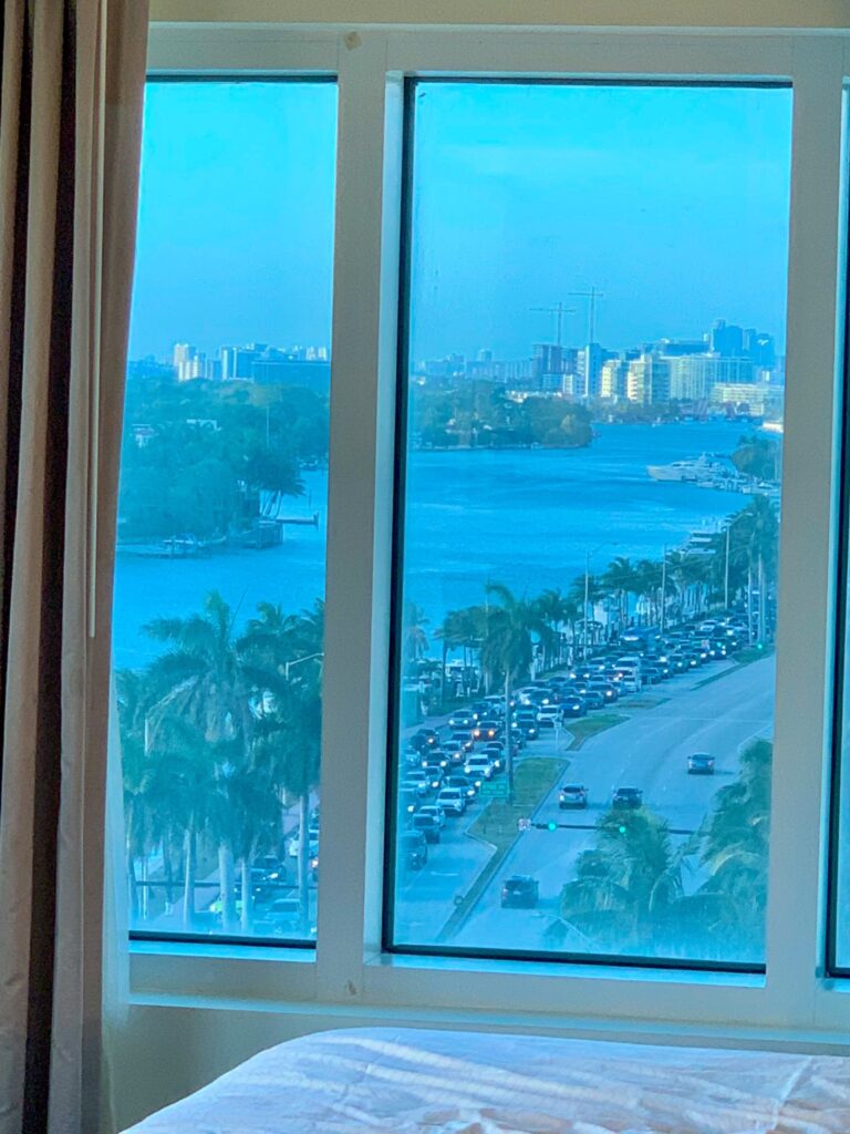 Bedside window framing Indian Creek, Collins Avenue traffic and the palm lined causeway