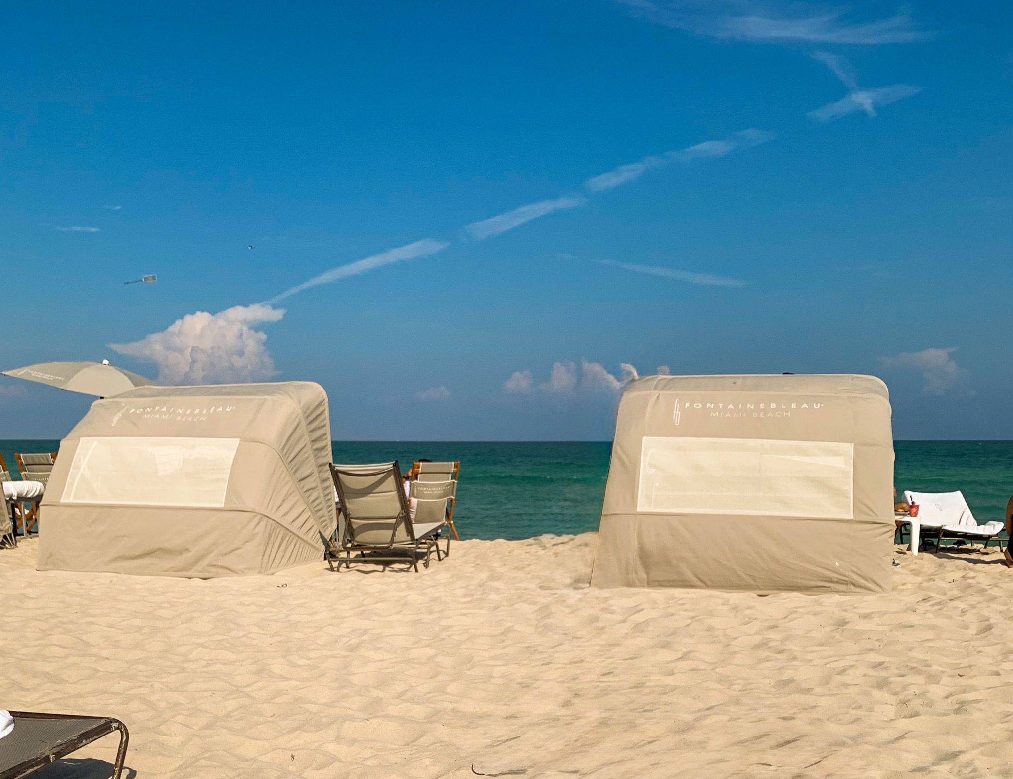 Two canvas beach cabanas facing the turquoise water