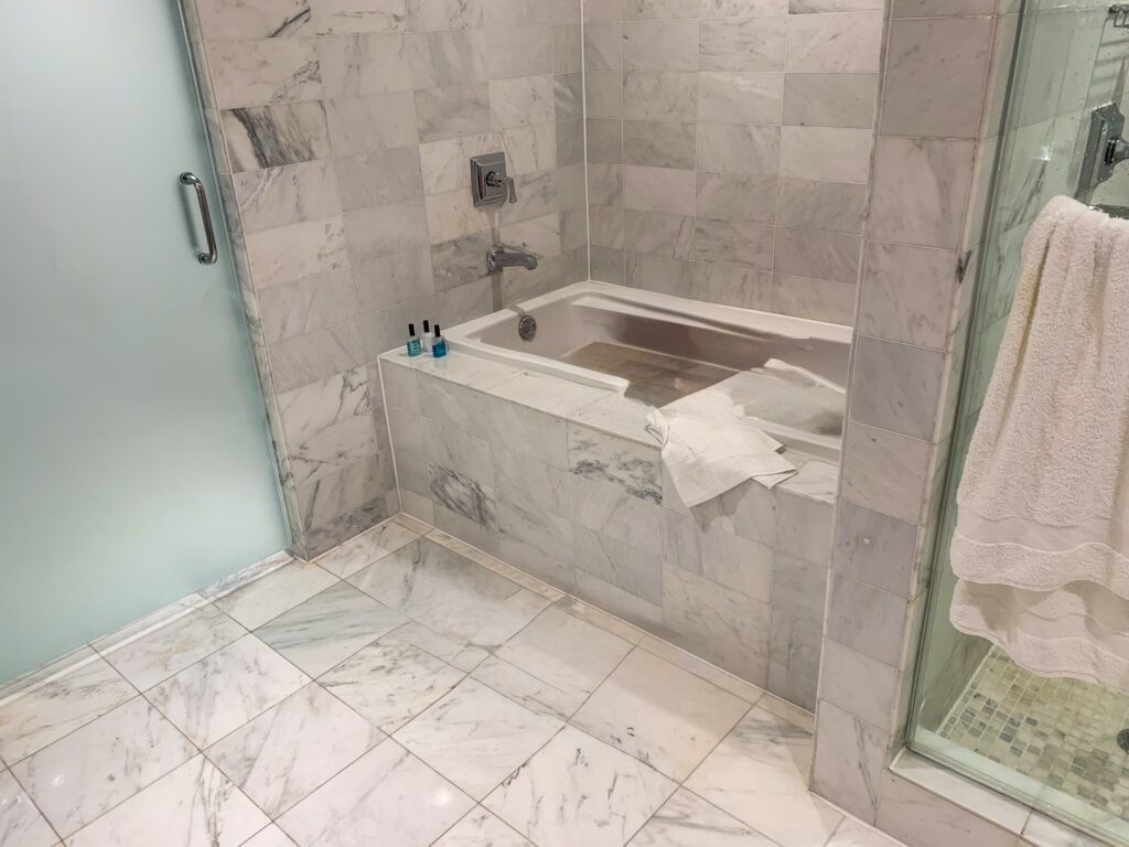 Marble clad bathroom with a deep soaking tub and glass shower