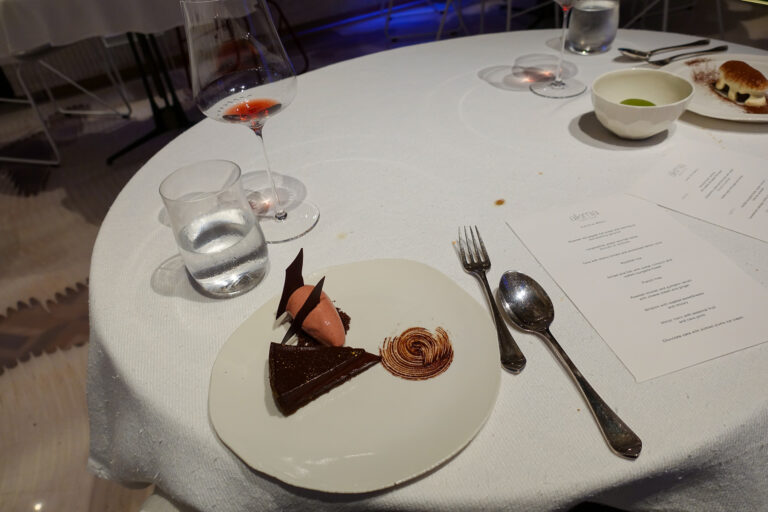 A wedge of dark chocolate cake with a chocolate curl, the cleared table and menu around it