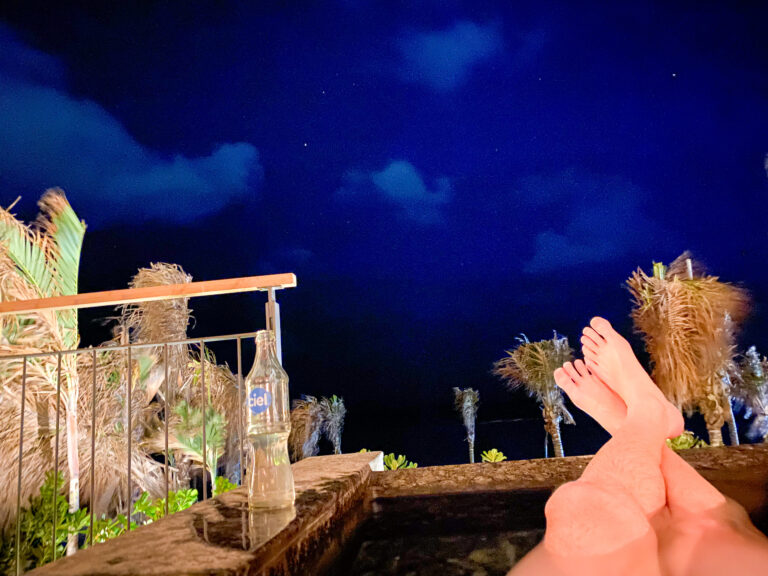 Bare feet on the rail of the terrace under a deep blue night sky