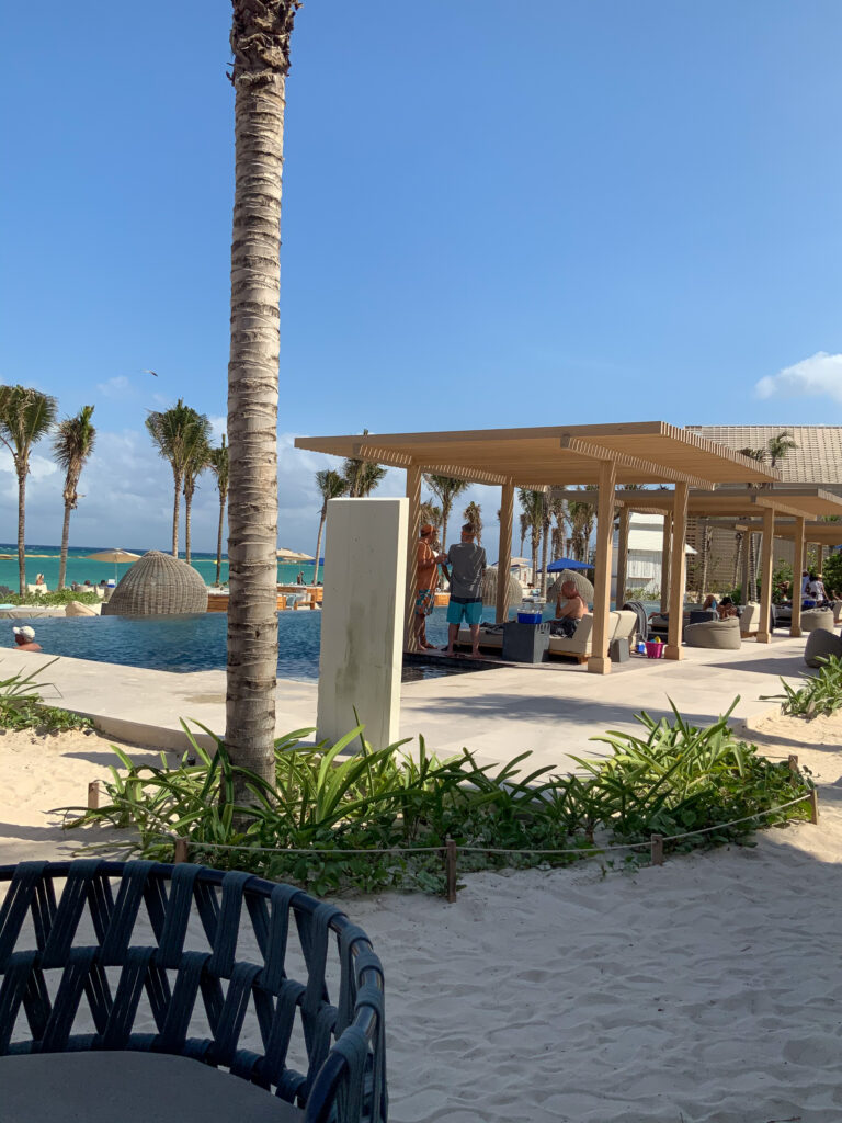 Cabanas and loungers around the beachfront pool under palms