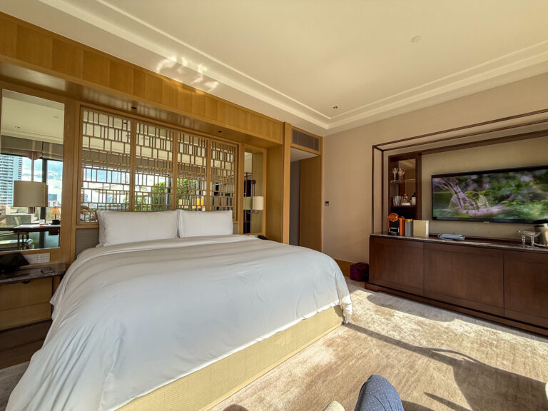 A white-dressed bed against wood panelling, the river visible through the window beyond