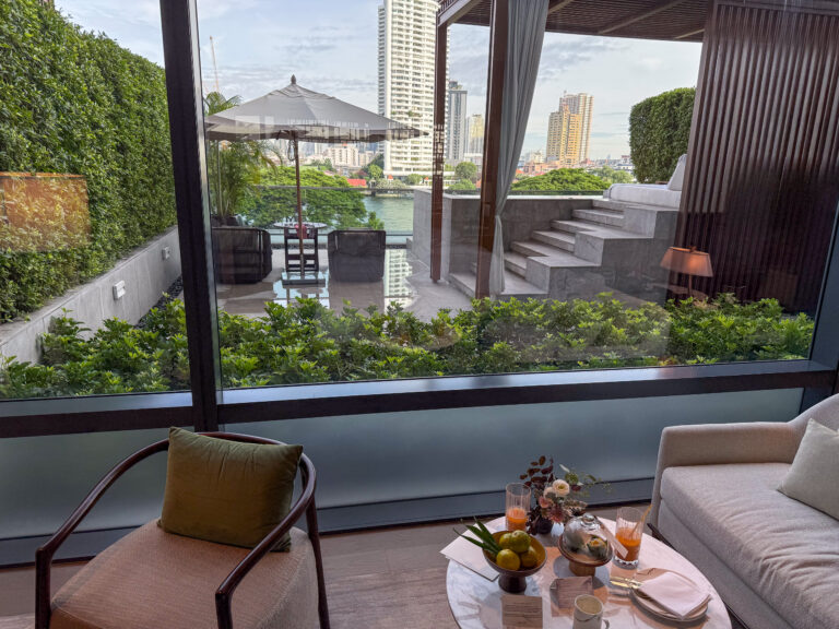 The planted terrace and river seen from the living room, a drink on the low table