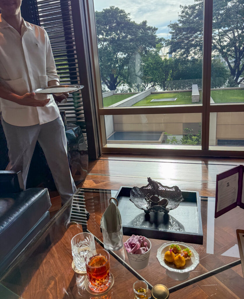A member of staff carrying plates through the suite, the garden through the glass