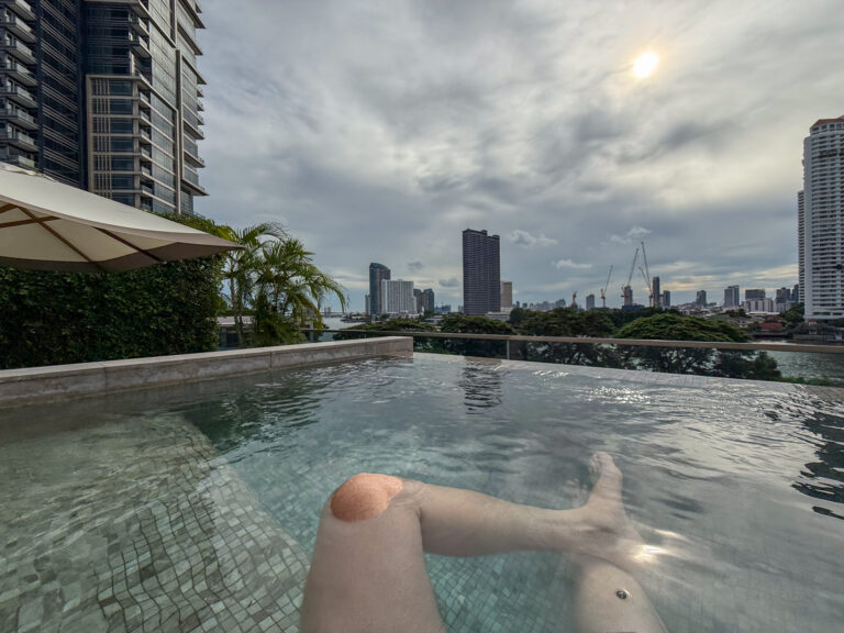 The edge of the plunge pool with the city skyline under heavy cloud
