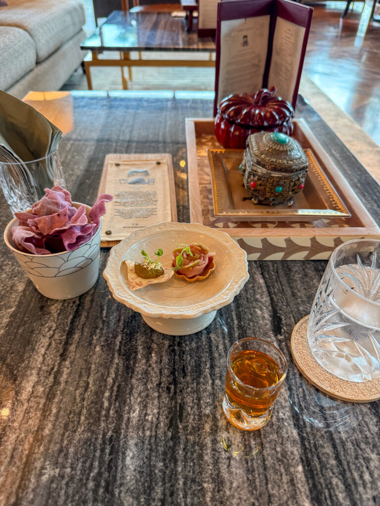 Two canapes on a stone stand with a menu card and a glass of whisky