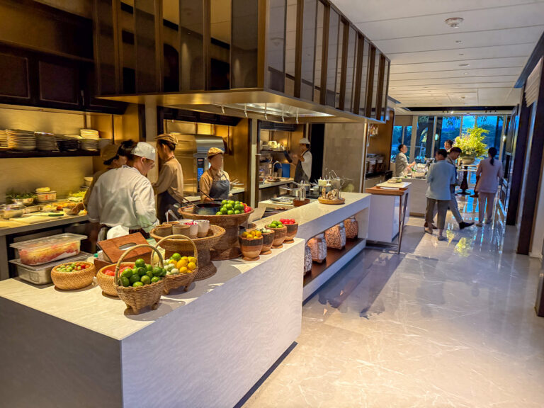 The open kitchen at breakfast, baskets of fruit along the pass and cooks at the range