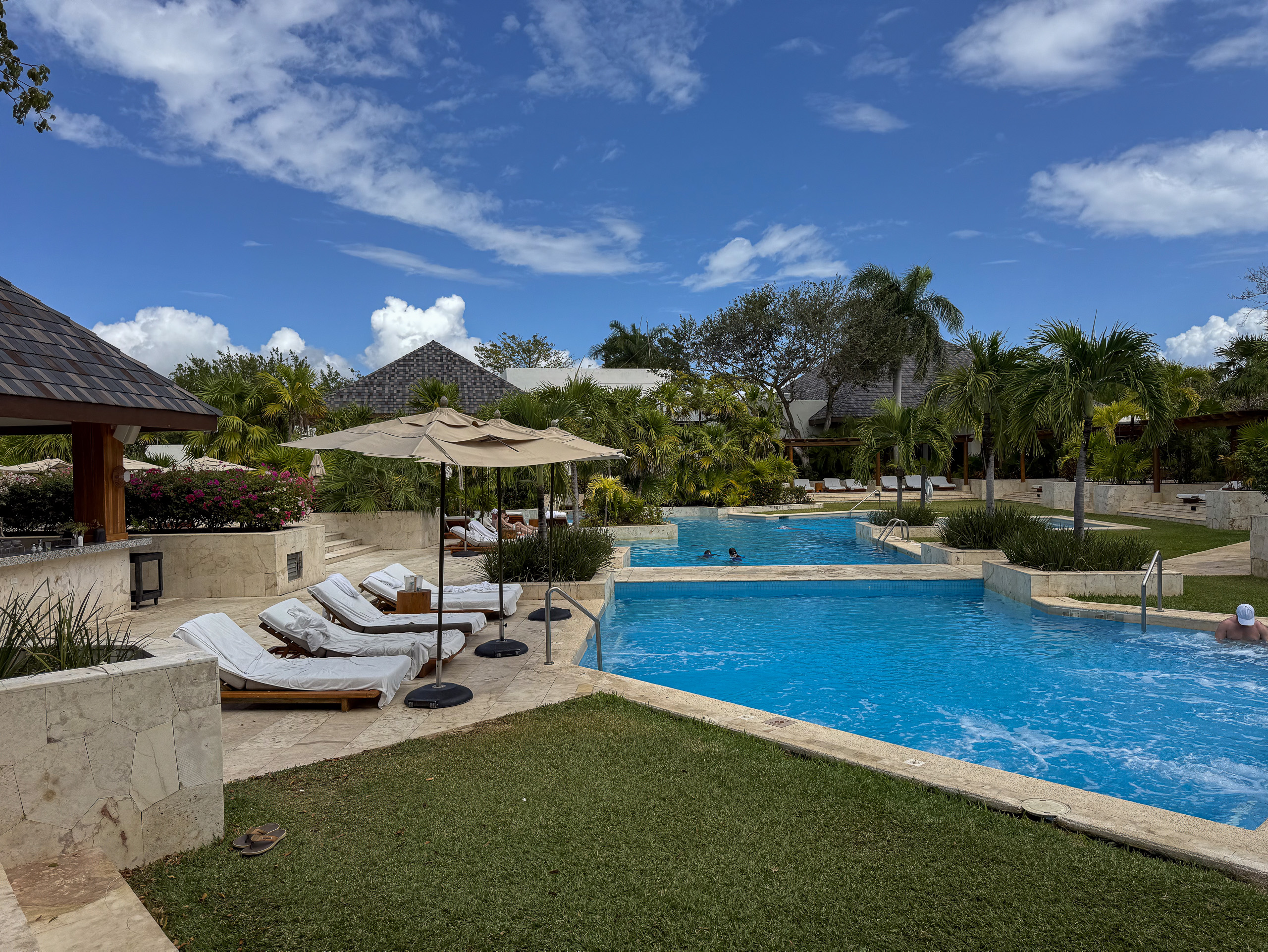 The main pool at Fairmont Mayakoba, loungers and a parasol on the limestone terrace with palms behind