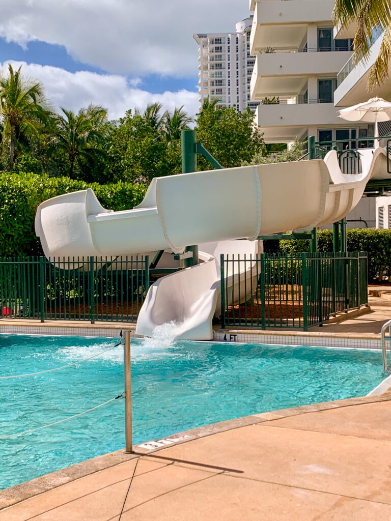 White waterslide curving down into the family pool below the balconies