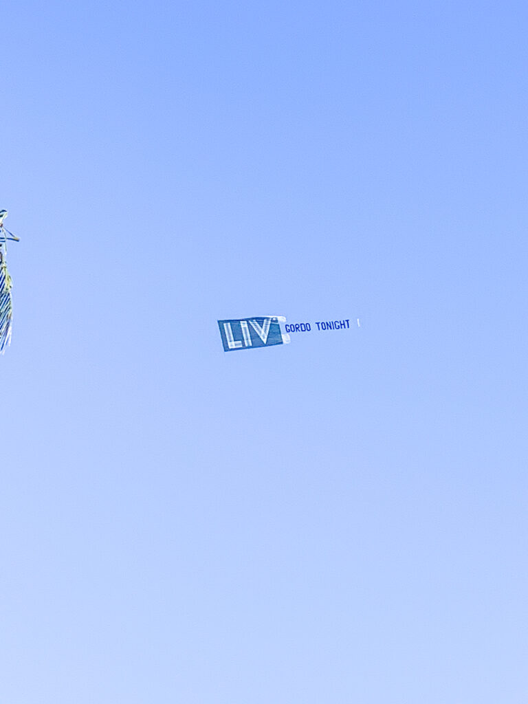 Aerial advertising banner drifting across clear blue sky above the hotel