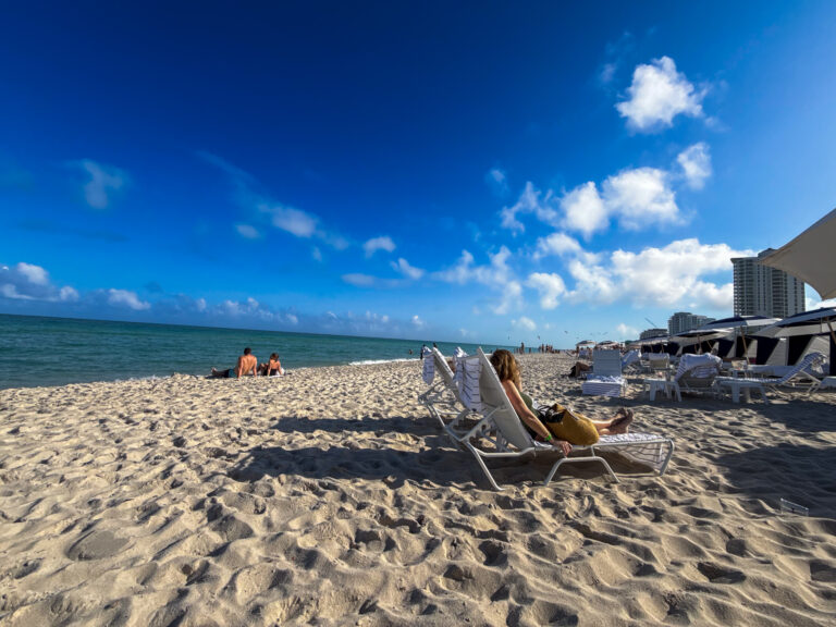 Beach loungers on the wide sand with the tower behind