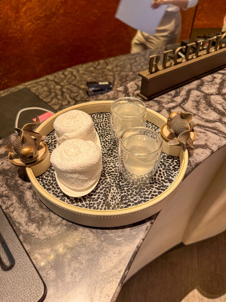 Two rolled towels and glasses of water on a tray set on a marble table