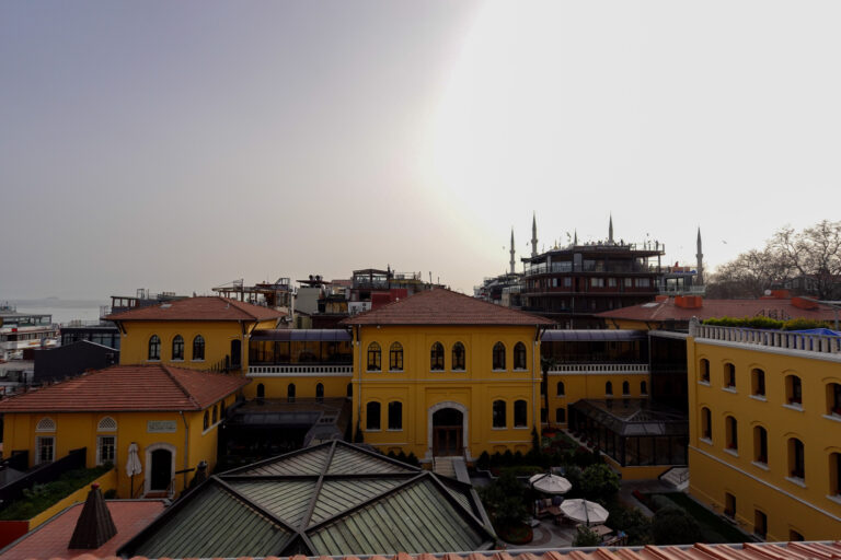 The ochre wings of the hotel and the rooftops of Sultanahmet under a pale, hazy sky