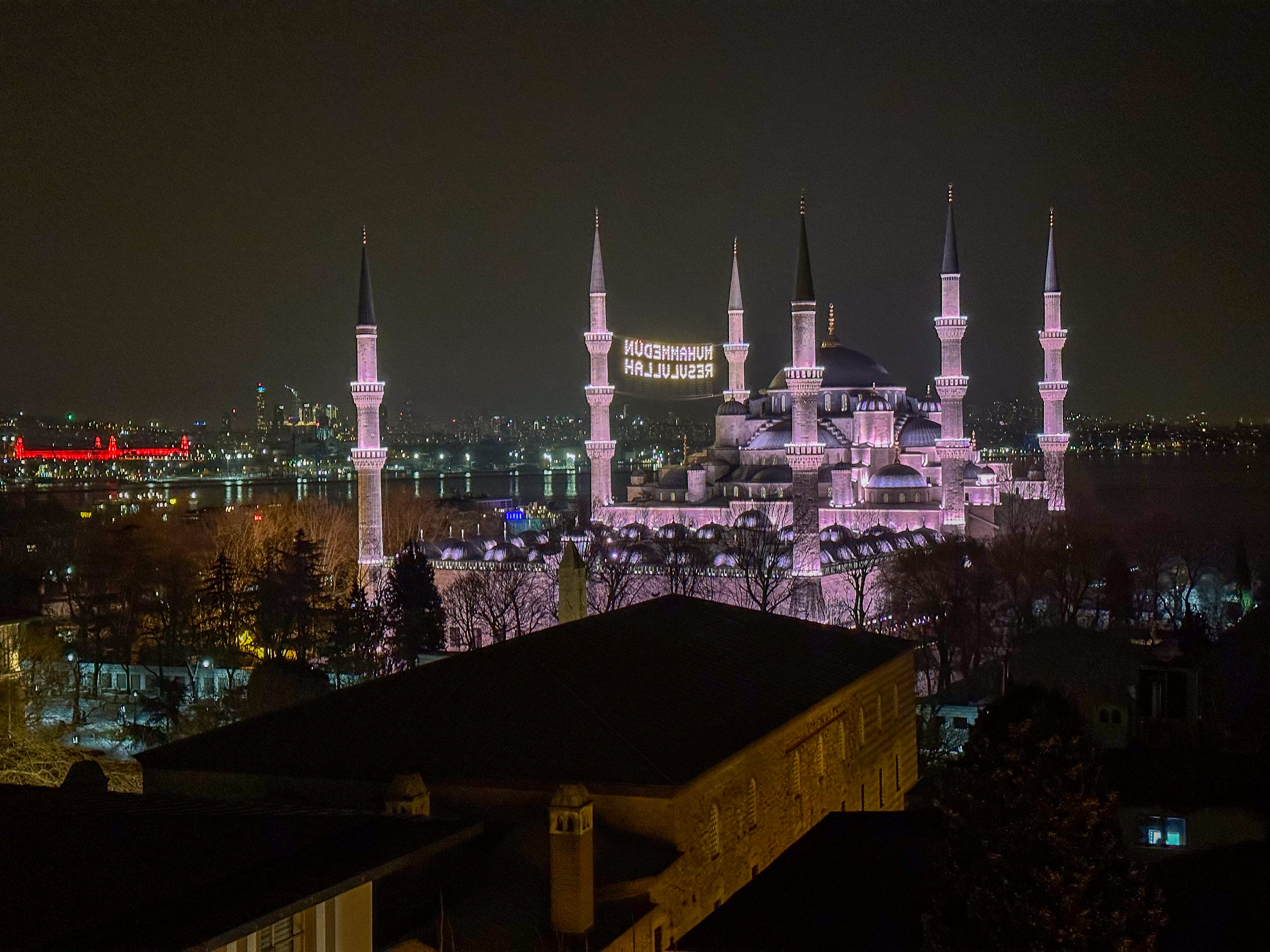 The mosque's minarets picked out in floodlight above the silhouetted rooftops