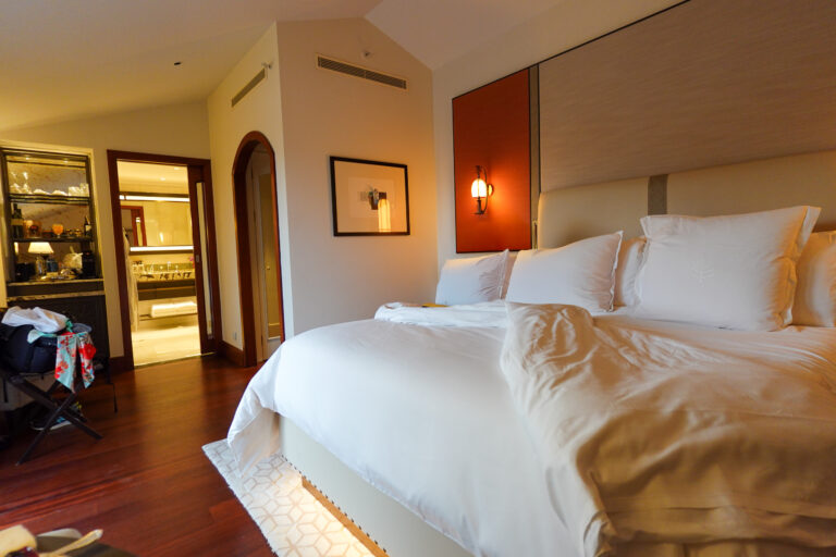 White linen and a warm bedside lamp, with the door to the sitting room ajar