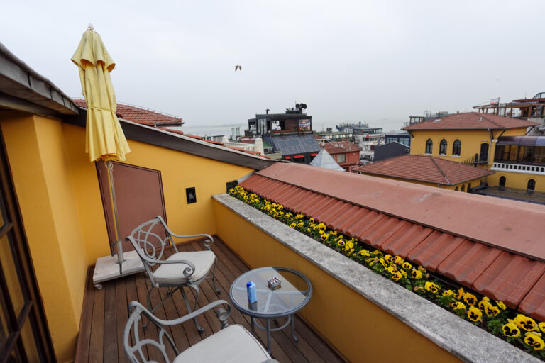 A parasol, two chairs and planted boxes on a private roof terrace above the tiles