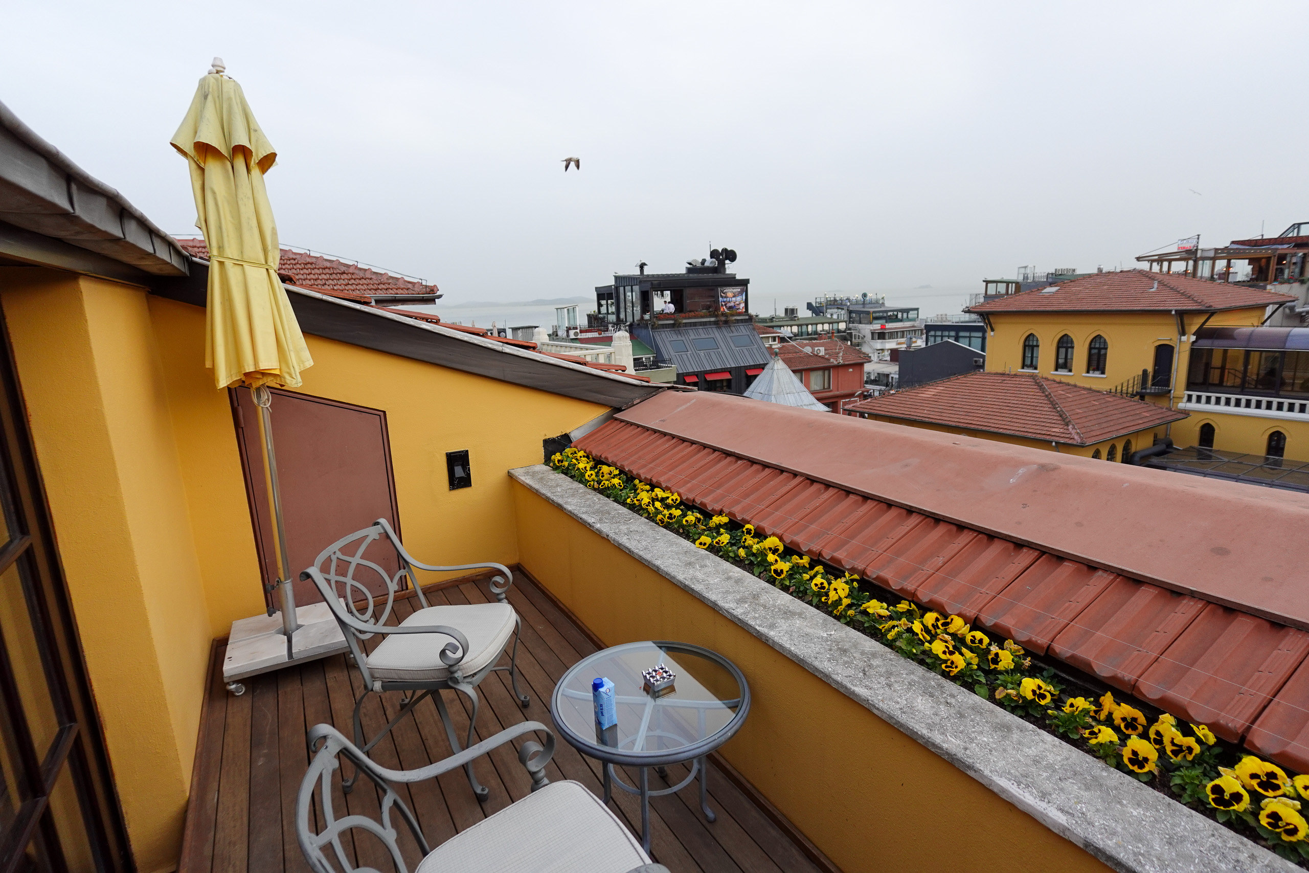 A parasol, two chairs and planted boxes on a private roof terrace above the tiles