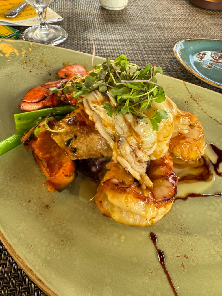 Pulled pork and prawns under a tangle of greens, sauce drawn round the rim