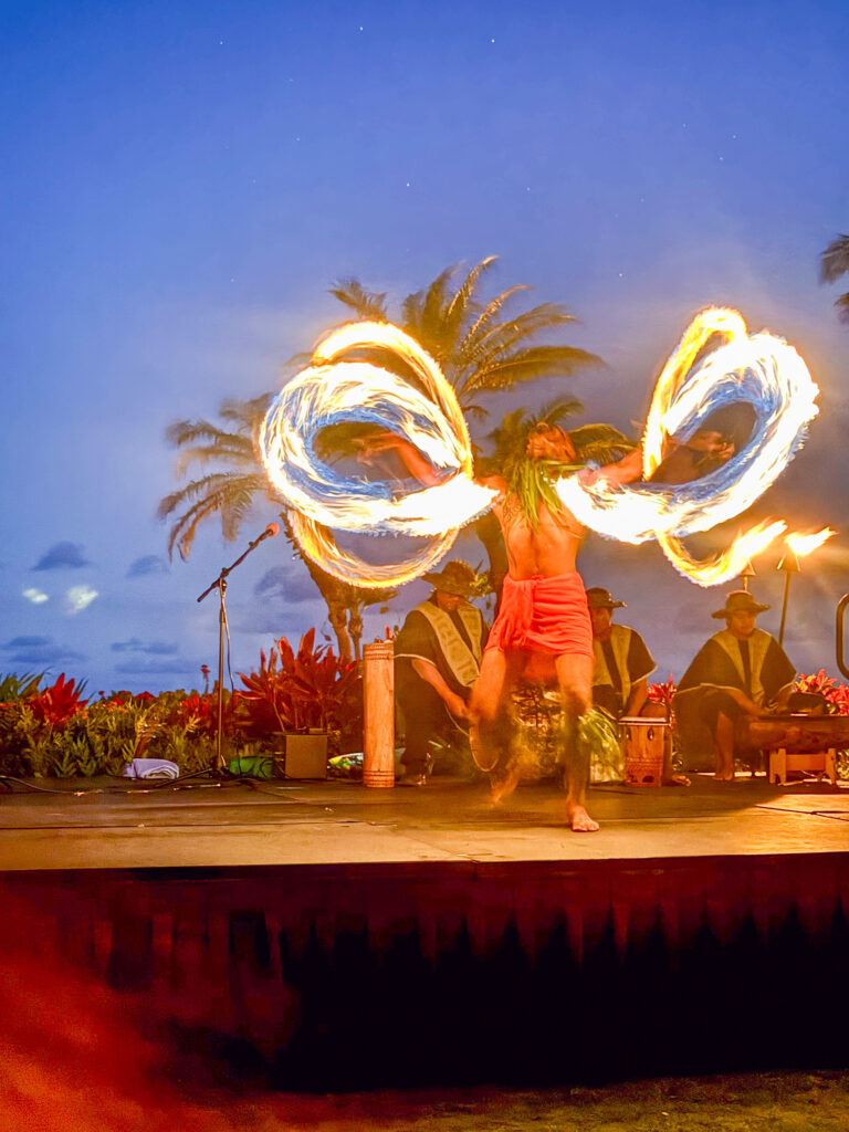 A fire dancer spinning at dusk, the flames drawn out into two rings