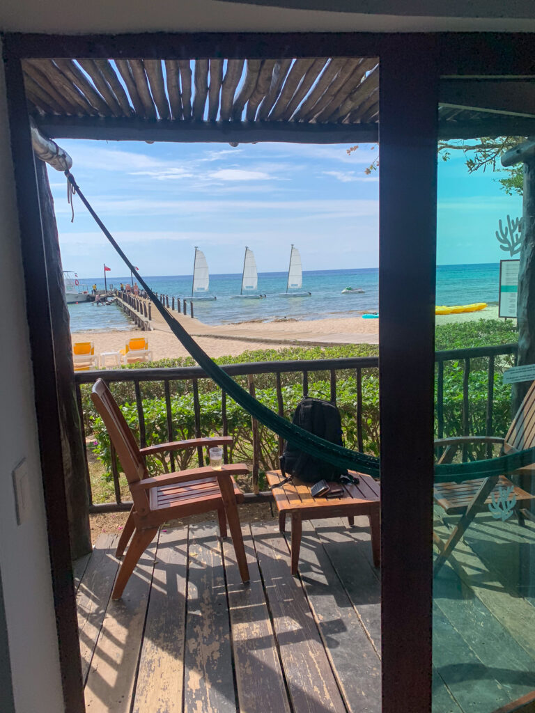 A hammock strung across a balcony, the door open onto palms and the sea beyond