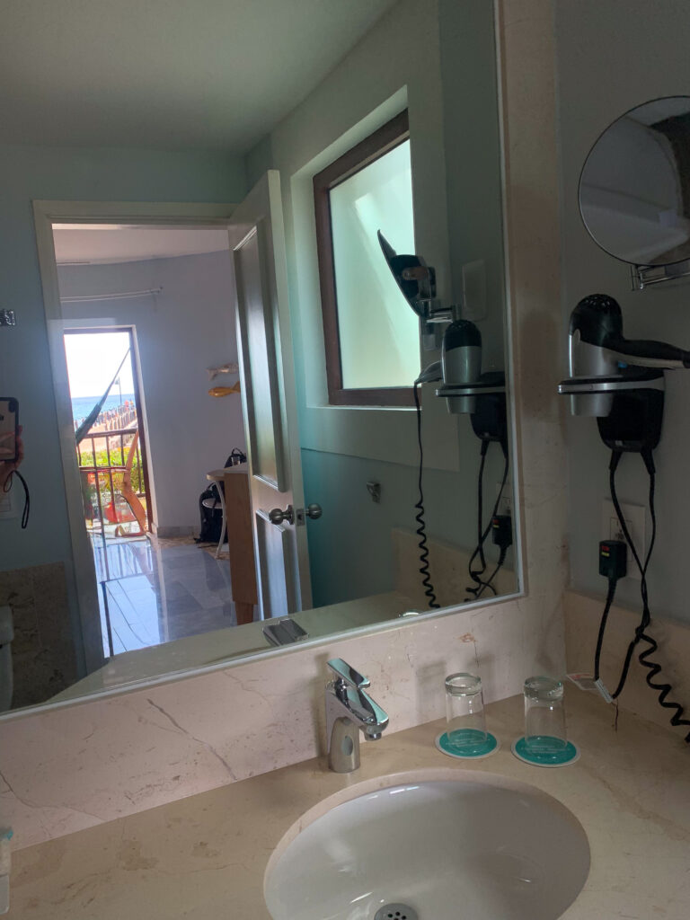 The bathroom mirror catching the window and the corridor light behind it
