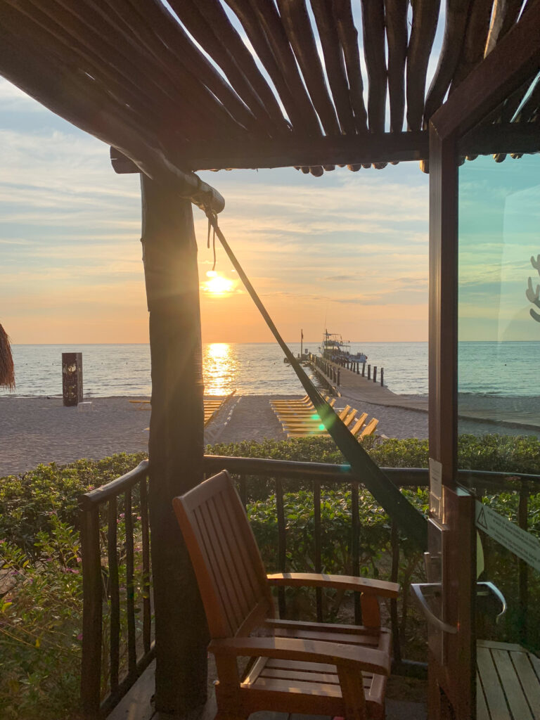 Late light across the water, seen from a covered terrace with a hammock and chairs