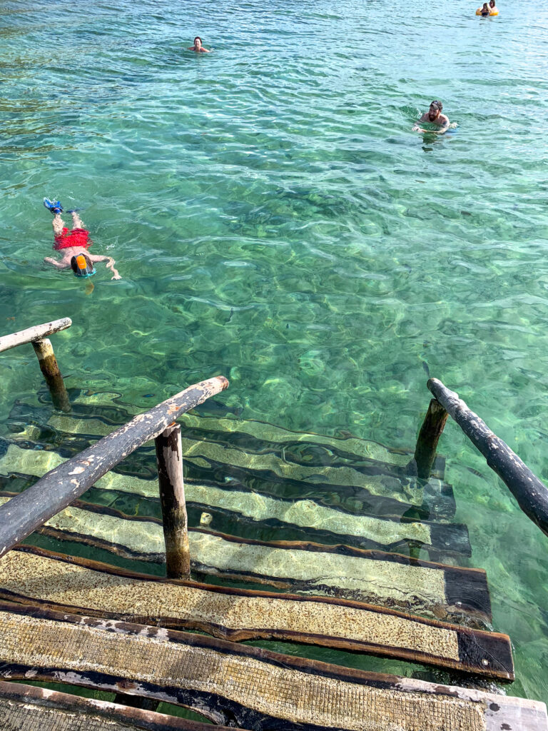 Wooden steps down into the sea, snorkellers out beyond them