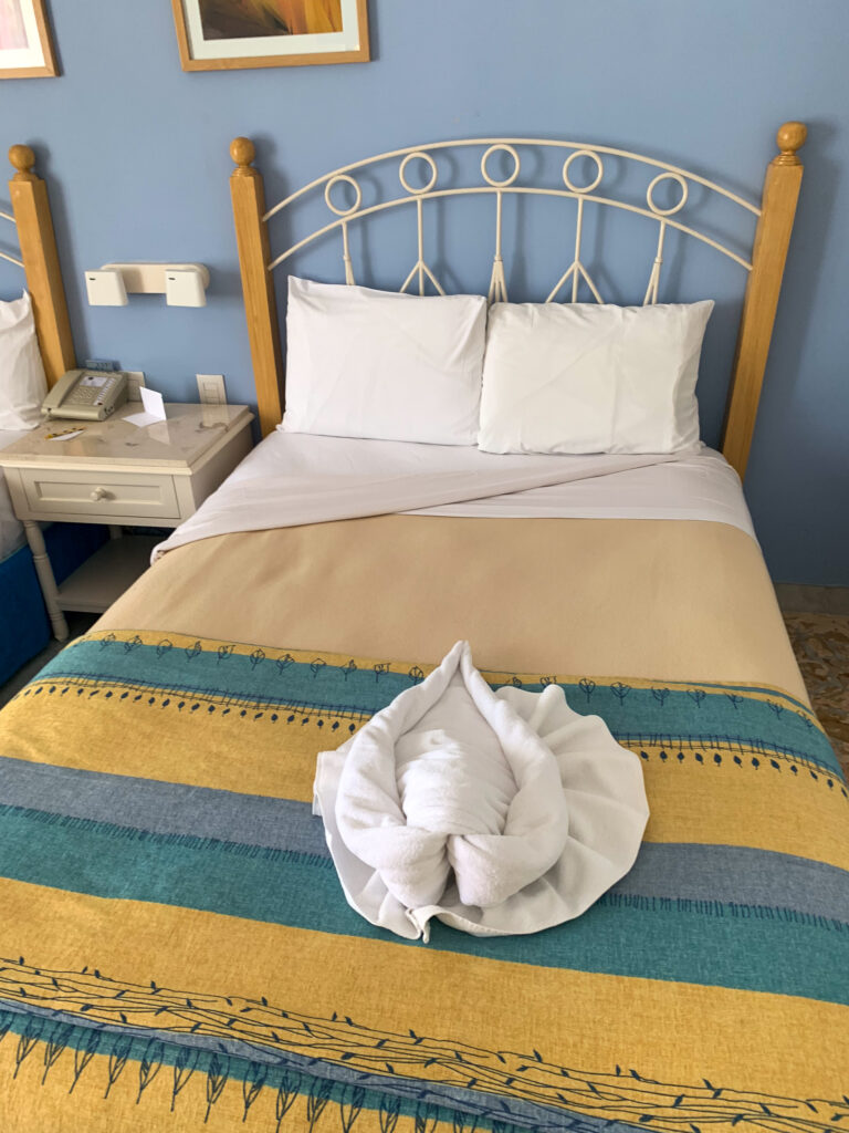 A bed under a wrought-iron headboard, a folded towel set at its foot