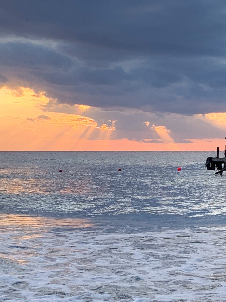 Cloud lit orange above the sea, the surf running in over the sand