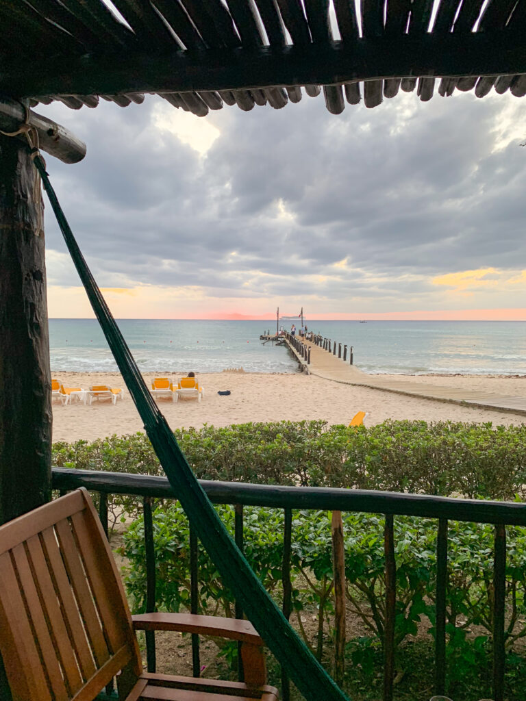 Looking out through the balcony rail and thatch to the sand and the sea